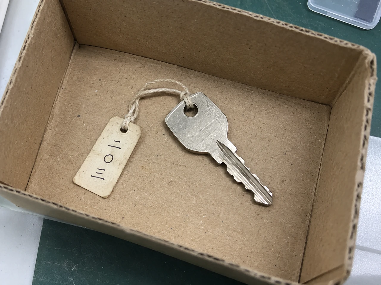 保管箱の底に置かれた鍵一本。鍵の穴に通したひもで、「二〇三」と手書きされた紙札が付いている。