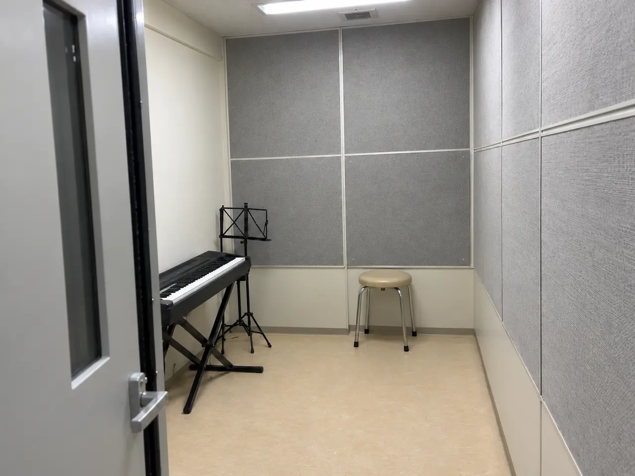 施工前と同じ灰色の吸音パネルで囲まれた練習室。工具は片付けられ、内張りは再び壁に固定されている。背もたれのない丸椅子が、内張りに近接した位置へ寄せられ、部屋の中央は空いている。